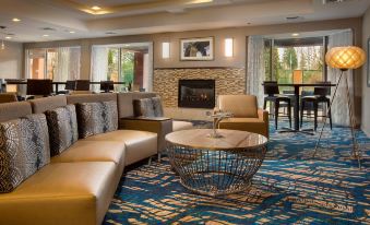 a living room with a couch , chairs , and a coffee table in front of a fireplace at Courtyard Seattle North/Lynnwood Everett