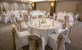 a well - decorated banquet hall with several tables covered in white tablecloths and chairs arranged for a formal event at Horsley Lodge