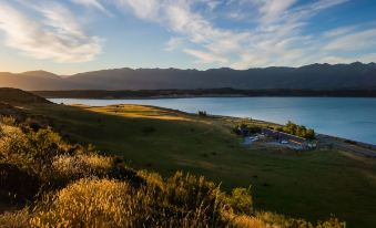 a beautiful landscape with a vast lake surrounded by grassy hills and mountains in the background at Lakestone Lodge