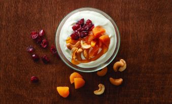 a bowl of yogurt topped with fruit and nuts , accompanied by a spoon and a sprig of fruit at SpringHill Suites Philadelphia Willow Grove