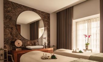 a luxurious spa setting with two massage tables , a large mirror , and a window offering views of the surrounding environment at Valverde Sintra Palacio de Seteais