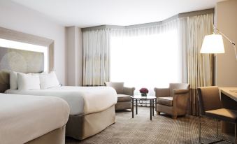 a hotel room with two beds , a couch , and a window , all decorated in white and brown colors at Novotel Montreal Center