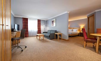 a hotel room with a bed , desk , and couch , as well as a desk and chair at DoubleTree by Hilton Swindon