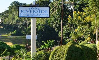a sign for the riverside hotel & conference center is posted on a pole in front of bushes at Riverside Apartments