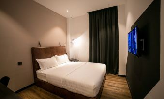 a hotel room with a king - sized bed and a flat - screen tv mounted on the wall at Eureka Hotel Penang