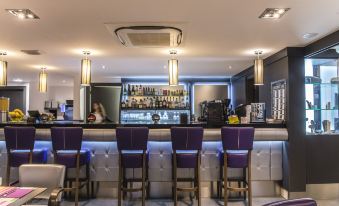 a modern bar with a purple counter and white chairs , surrounded by shelves filled with bottles at Suite Home Porticcio