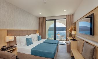 a modern hotel room with a large bed , blue sheets , and a view of the ocean at Hotel Perla