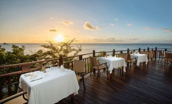 a wooden deck overlooking the ocean , with several tables and chairs set up for dining at Cap Maison Resort & Spa