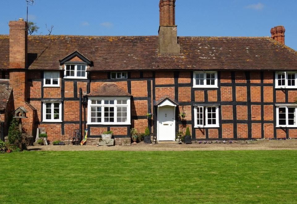 a large red brick house with a white door and a green lawn in front at Moor Court Farm