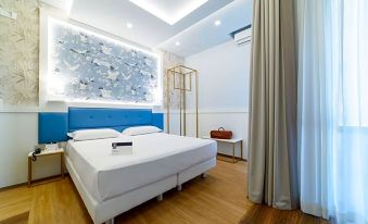 a modern bedroom with white bed , blue headboard , and wooden flooring , as well as a bathroom with a white bathtub and towel rack at Hotel Palace