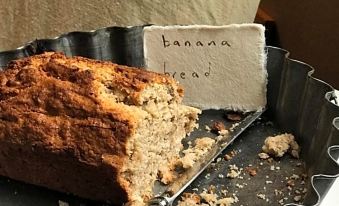 a metal pan with a slice of banana bread on it , accompanied by a knife at Radnor House