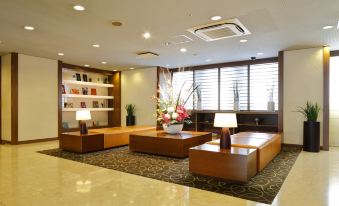 a modern hotel lobby with wooden furniture , a vase of flowers , and a bookshelf filled with books at Hotel Resol Machida