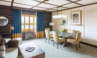 a luxurious hotel suite with a large dining table , comfortable chairs , and a view of the ocean at Fairmont le Chateau Montebello
