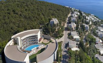 aerial view of a modern building surrounded by trees and water , with a swimming pool in the foreground at Duja Bodrum