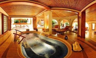 a luxurious indoor pool area with wooden ceiling , surrounded by comfortable seating and hot tub at Tabacon Thermal Resort & Spa