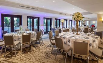 a large banquet hall filled with round tables and chairs , ready for a formal event at The Kingsley Bloomfield Hills - a DoubleTree by Hilton