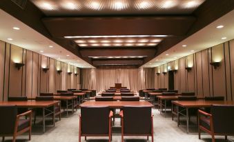 a large conference room with rows of wooden tables and chairs , creating an auditorium - like atmosphere at Kawana Hotel
