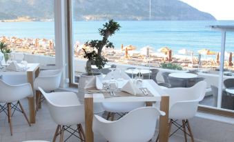 a restaurant with white chairs and tables , overlooking the ocean , under a large glass ceiling at Konstantinos Palace