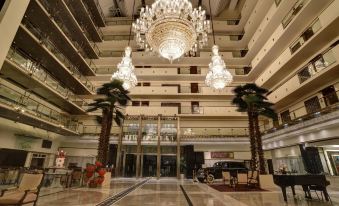 a grand hotel lobby with a large chandelier hanging from the ceiling and palm trees surrounding the space at Pearl Continental Hotel, Lahore