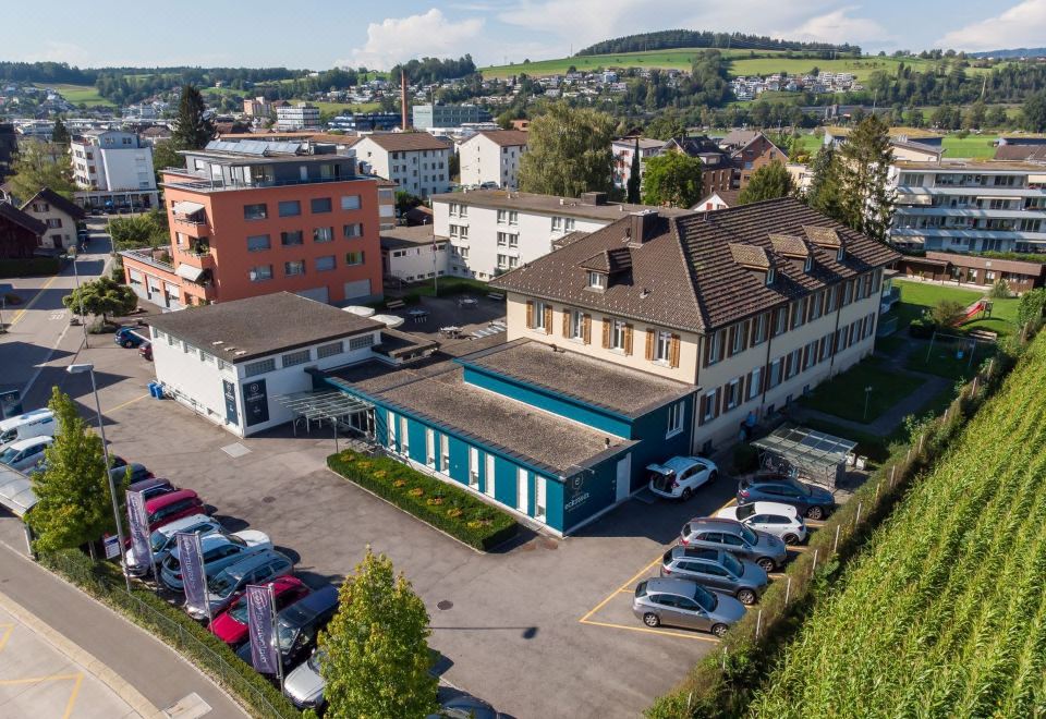 aerial view of a large building surrounded by a parking lot , with several cars parked in front of it at Dialoghotel Eckstein