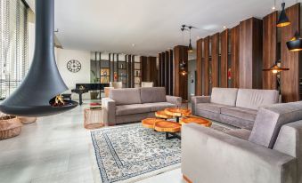 a modern living room with a gray couch , wooden coffee table , and a large fireplace at AP Maria Nova Lounge