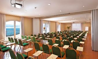 a conference room with rows of green chairs and desks set up for a meeting at Grand Hotel Baia Verde