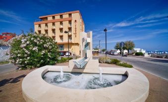 a hotel with a large fountain in front of it , surrounded by trees and benches at Hotel Florence