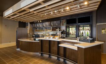 a modern restaurant with a wooden ceiling , brown countertops , and a large window showing various food items at Courtyard Bay City