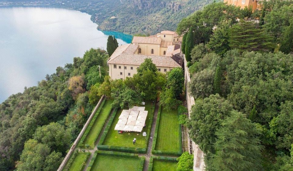aerial view of a castle surrounded by lush greenery , with a lake in the background at Villa Palazzola