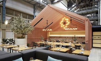 an open - air dining area with a wooden ceiling , black couches , and various dining tables and chairs at Ovolo Woolloomooloo