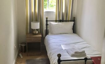 a small bedroom with a single bed , curtains , and a lamp on a side table at Sunny City