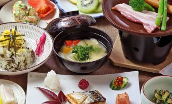 A table is filled with plates and bowls containing various types of food, including meat, vegetables, and other dishes at Minshuku Asogen
