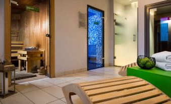a modern bathroom with a green bench , white tiles , and a blue door reflecting the outside view at Park Inn by Radisson Katowice