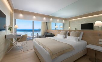a luxurious bedroom with a king - sized bed , a flat - screen tv , and a view of the ocean at Mediterranean Hotel