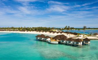 a tropical beach resort with wooden bungalows , clear blue water , and white sand , under a sunny sky at Sun Siyam Olhuveli