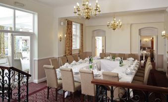 a large dining room with a long table set for a formal dinner , complete with multiple chairs , wine glasses , and a chandelier at Letchworth Hall