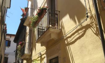a narrow street with buildings on both sides , one of which has balconies and plants at Legacy