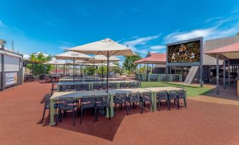 an outdoor dining area with several tables and chairs , surrounded by a grass - covered field at Comfort Inn & Suites Karratha