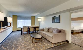 a living room with a beige couch , coffee table , and dining area in the background at Holiday Inn Staunton Conference Center