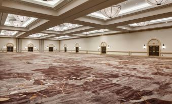 a large , empty conference room with a carpeted floor and white walls , illuminated by hanging lights at The Westin Rancho Mirage Golf Resort & Spa