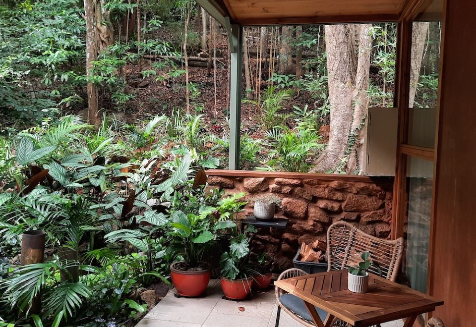 a wooden patio with a table and chairs , surrounded by greenery and featuring potted plants at Treetops Montville