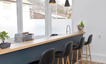 a modern kitchen with wooden flooring , black pendant lights , and a long counter with stools at Hotel Terra