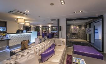 a modern hotel lobby with a white couch , purple seating , and a tv mounted on the wall at Suite Home Porticcio