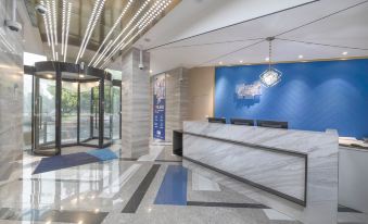 The lobby features a clean and modern design, highlighted by a spacious reception desk in an open concept layout at Holiday Inn Express Shanghai Gubei