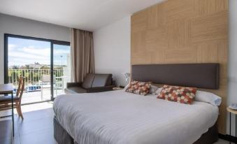 a large bed with white linens and a wooden headboard is in a room with a chair and sliding glass doors at Hotel Cap Negret