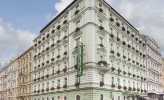 a large green and white building on a city street , surrounded by other buildings and people at Green Garden Hotel