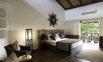 a spacious bedroom with a king - sized bed , hardwood floors , and a door leading to a patio at The Serai Bandipur