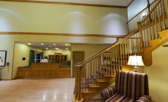 a large hotel lobby with a staircase leading to the second floor , a reception desk , and several chairs at Country Inn & Suites by Radisson, Rock Falls, IL