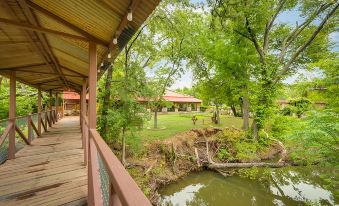 a wooden deck with a railing overlooks a pond and houses nestled in a green landscape at North Texas Jellystone Park