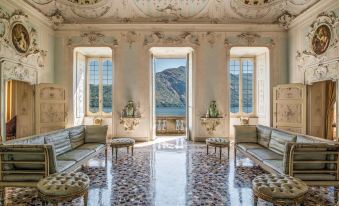 a grand living room with ornate furniture , marble flooring , and large windows overlooking a mountainous landscape at Grand Hotel Tremezzo